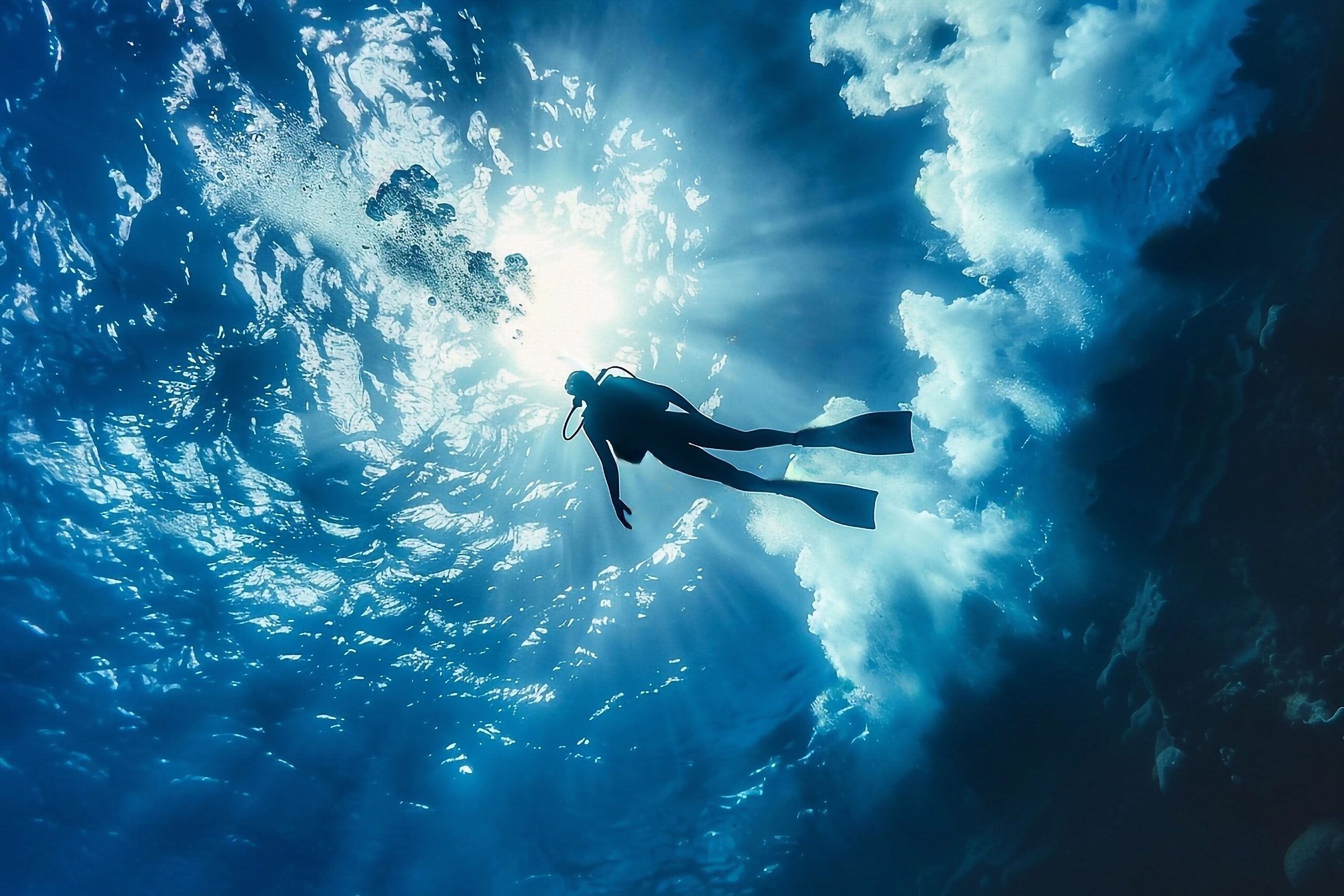 Silhouette of diver in blue sea with sun rays and sunlight
